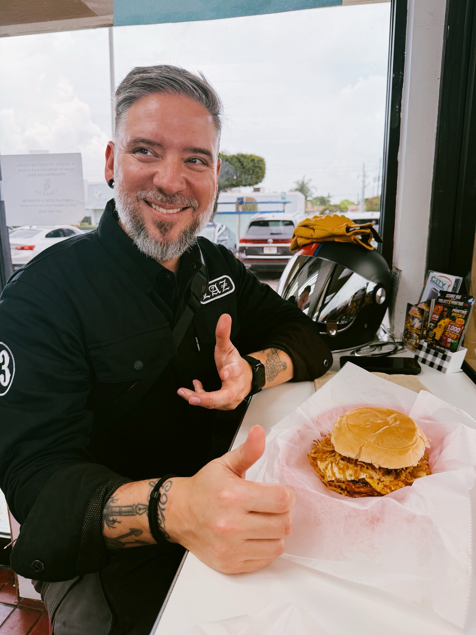 Laz grinning over a fried chicken sandwich at a lunch stop