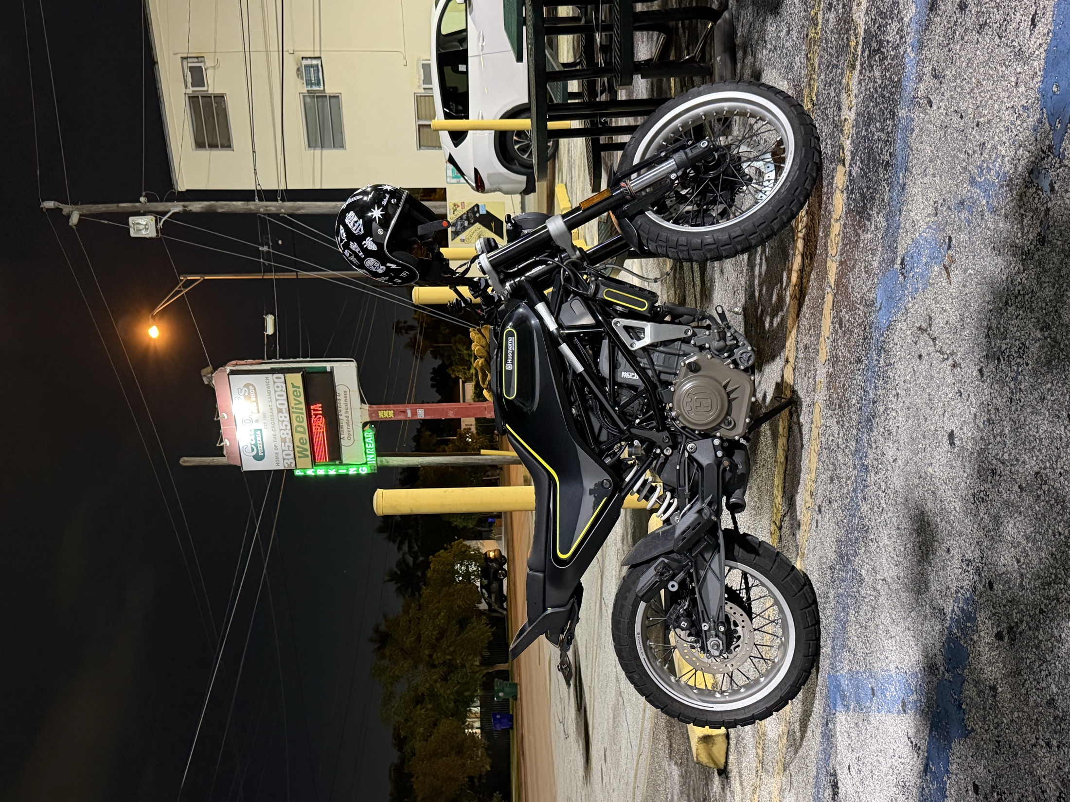 A Husqvarna parked at night under neon signs
