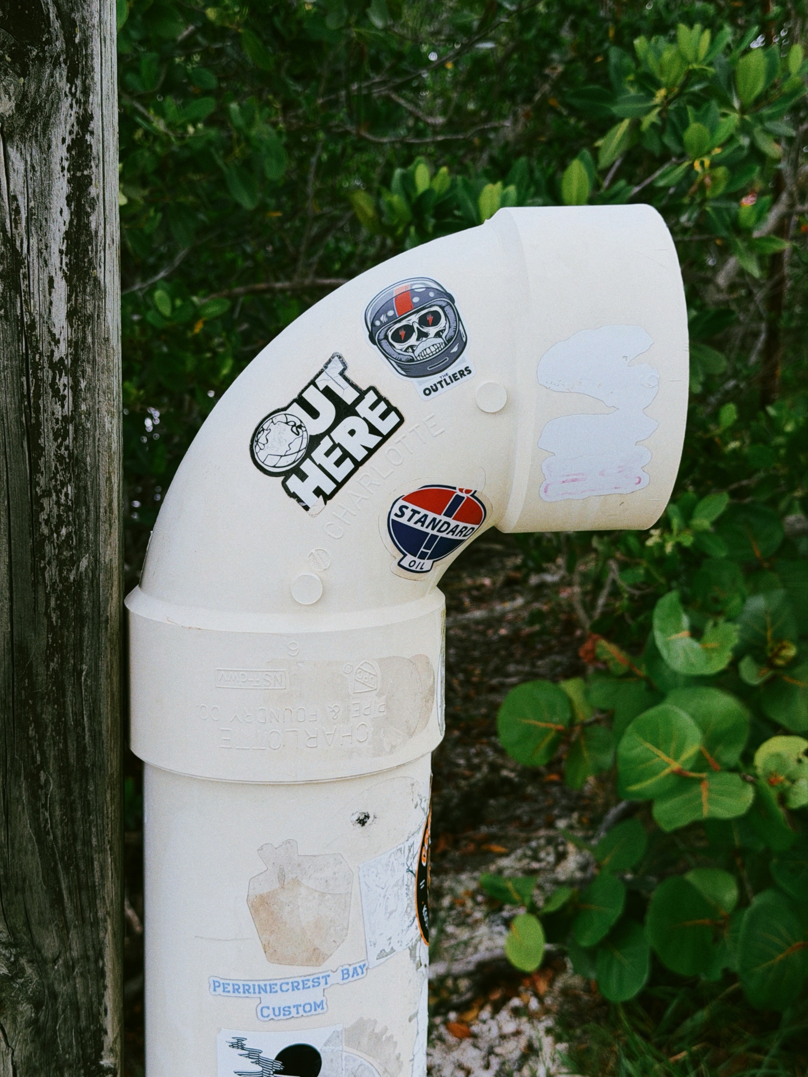 Outliers helmet sticker on a white pipe among trail markers