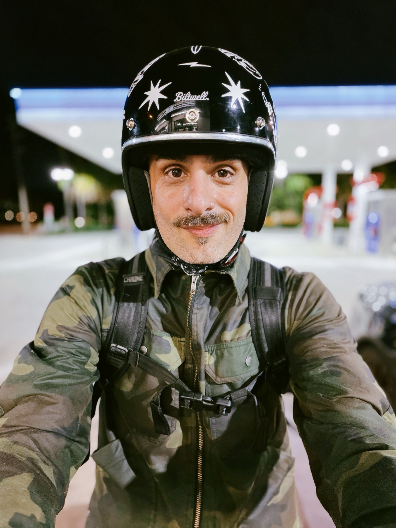 Agustin in a black helmet under gas station lights at night