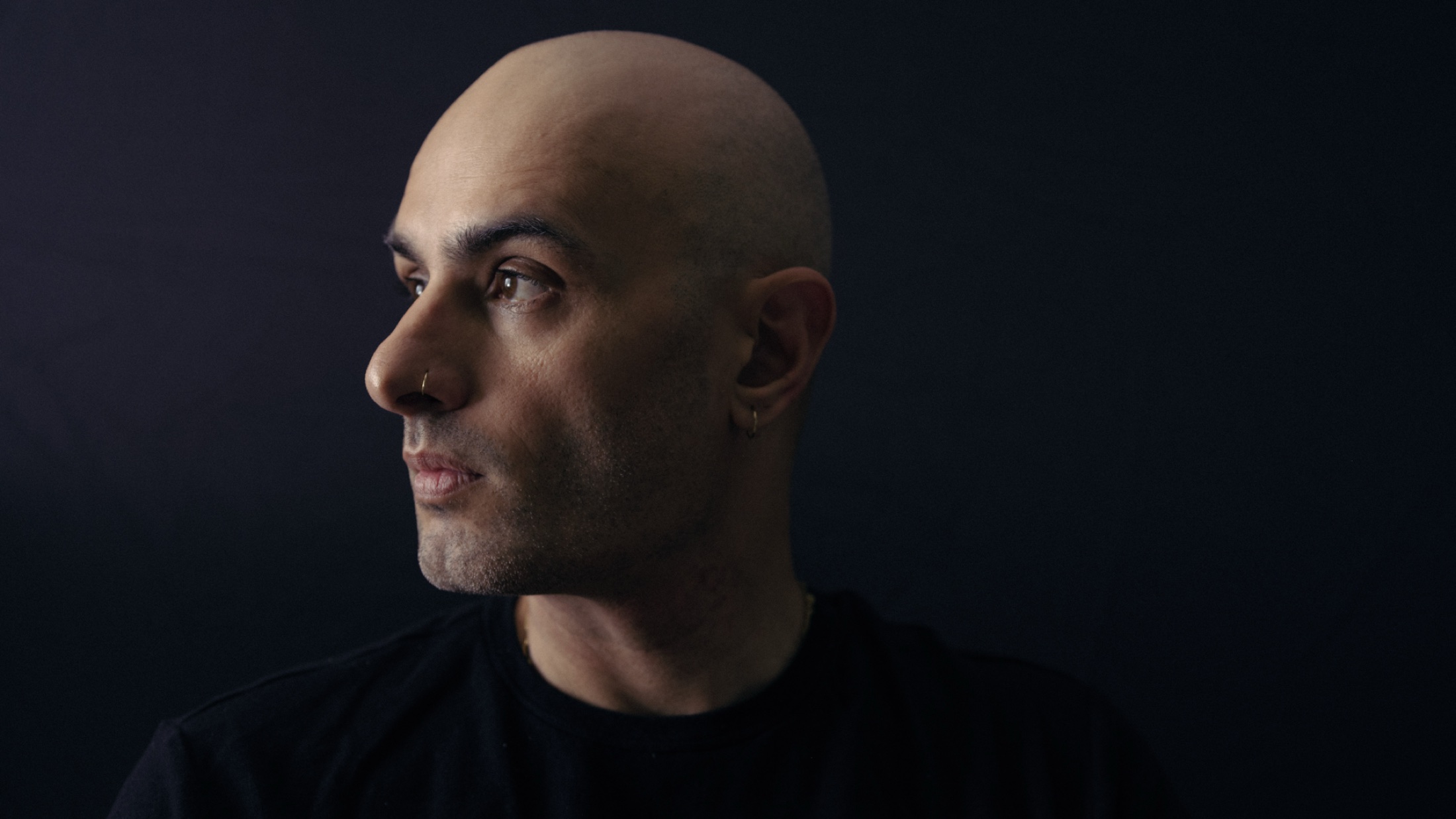 Agustin Sanchez in profile against a dark background, looking left